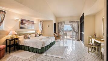Une chambre d’hôtel avec un lit, un bureau, une chaise, une vue sur la mer et un balcon.