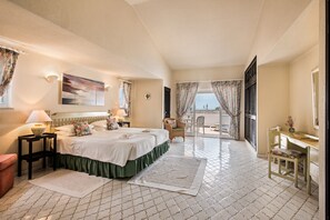Une chambre d’hôtel avec un lit, un bureau, une chaise, une vue sur la mer et un balcon.