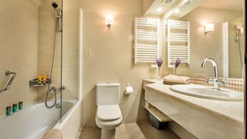 Ein modernes Badezimmer mit Badewanne, Toilette und Waschbecken, ausgestattet mit Handtuchhalter und Spiegel.