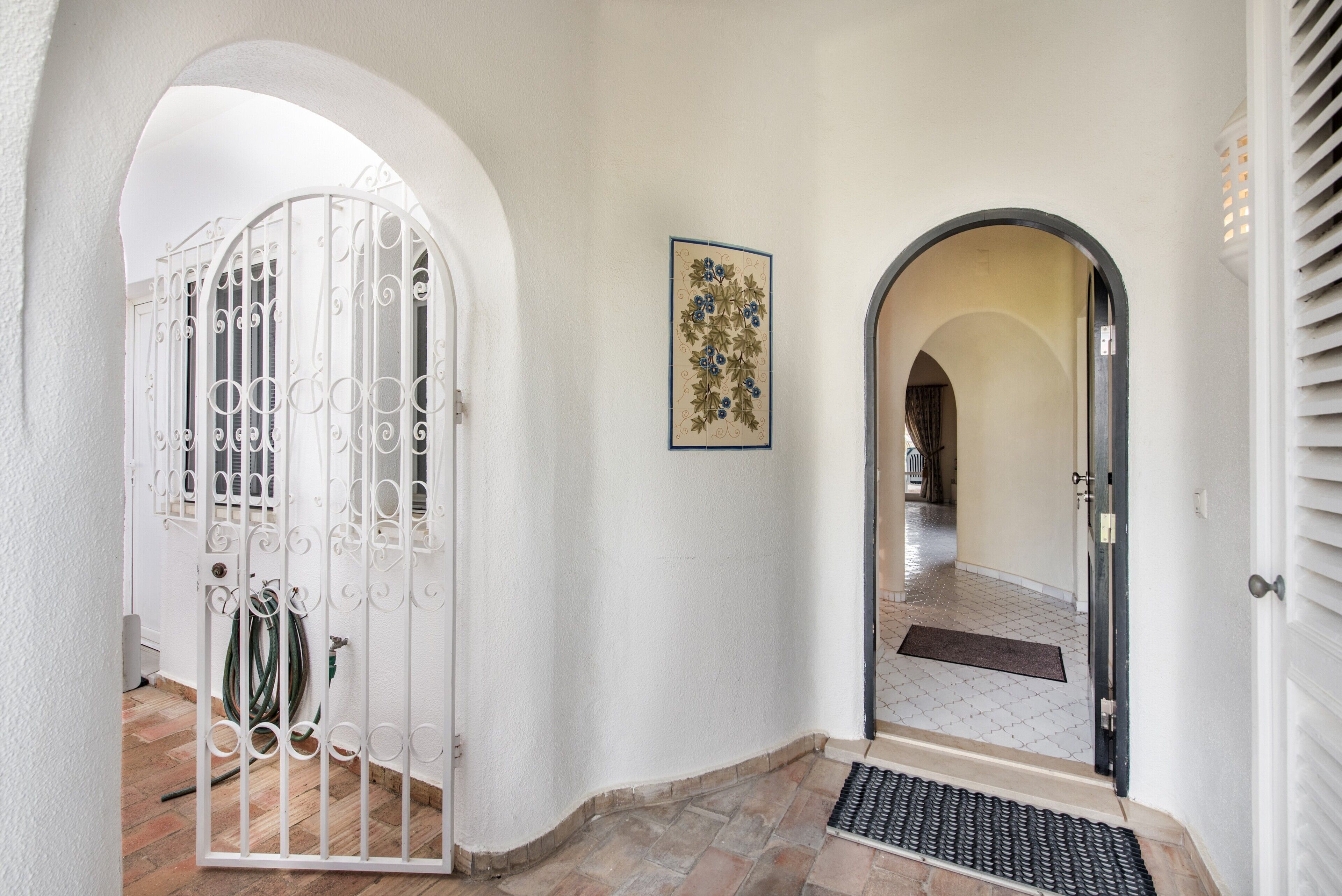 A hallway with a white door, a metal gate, and a doormat.