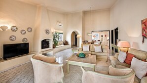 Una sala de estar amplia con chimenea, televisor y comedor con mesa y sillas.
