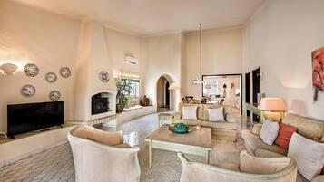 A spacious living room with a fireplace, a television, and a dining area with a table and chairs.