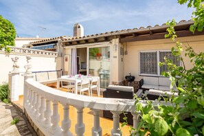 A patio with a table and chairs, a grill, and a glass door leading to an interior space. - Holiday Home 'Maison La Coquette' with Private Terrace, Wi-Fi and Air Conditioning (L'Escala)