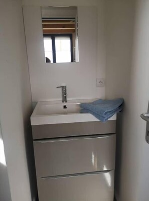 Une petite salle de bain comprenant un lavabo, un miroir et un porte-serviettes.