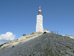 Une haute tour blanche, surmontée d’une antenne rouge et blanche, se dresse sur une colline rocheuse.