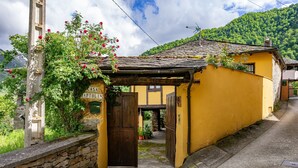Un edificio amarillo con pared de piedra, una puerta de madera y un letrero que dice 'CASA HARTOLI'.