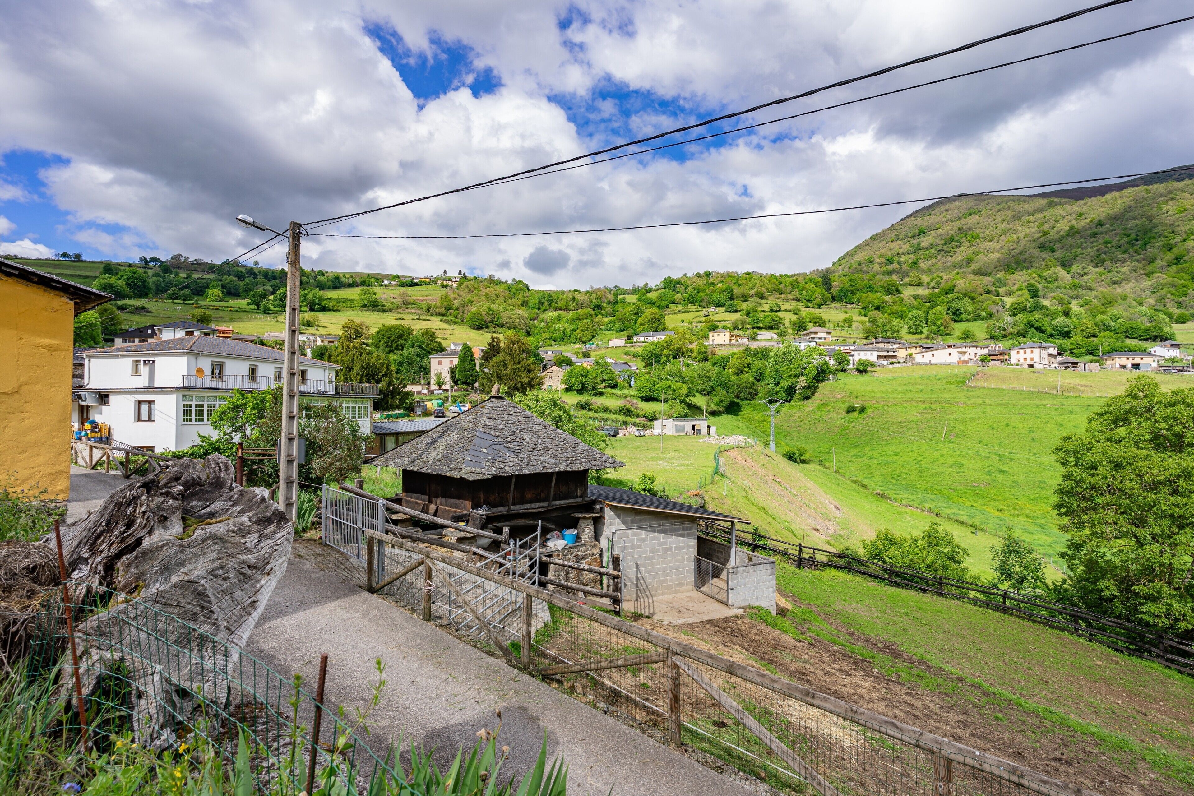 Un pueblo rural con casas, una estructura de madera y una zona cercada.