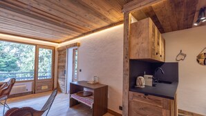 A wooden interior with a kitchen area, a dining table, and a bench.