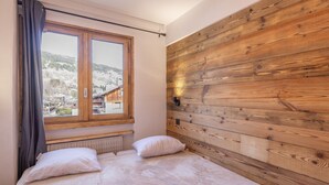 A bedroom with a wooden headboard, a window with curtains, and a bed with two pillows.