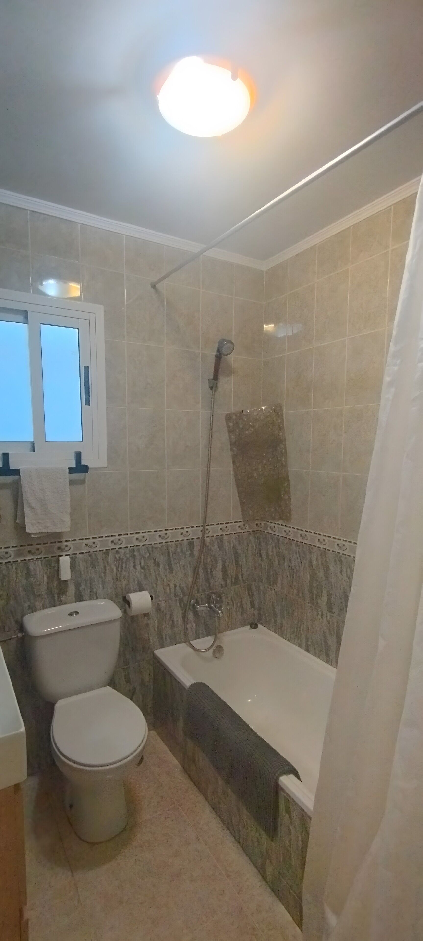 Une salle de bain comprenant des toilettes, une baignoire, une douche et une fenêtre.