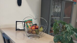 Un comptoir de cuisine avec un panier de fruits, une plante en pot et un meuble de rangement.