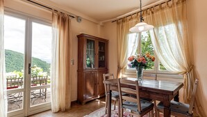 Ein Essbereich mit Holztisch und Stühlen, einem Schrank und Blick auf einen Balkon mit Gartenmöbeln.