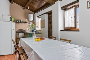 A kitchen with a white refrigerator, a microwave, a sink, and a wooden ceiling. There is a table with a white tablecloth and two lemons on it. - Apartment 'Cetareas 1' with Garden, Barbecue and Wi-Fi (Rinlo)