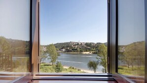 A view through a window of a riverside town with a prominent hill and a building with a tower. - Apartment 'Porto Douro - 2' with Shared Pool, Shared Terrace and Wi-Fi (Foz do Sousa)