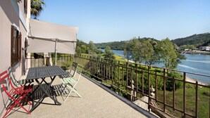 A balcony with a table and chairs, overlooking a river and greenery. - Apartment 'Porto Douro - 2' with Shared Pool, Shared Terrace and Wi-Fi (Foz do Sousa)