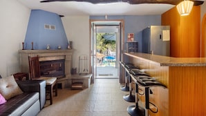 A modern kitchen with a bar area, a fireplace, and a view to the outside. - Holiday Home 'Porto Douro' with Private and Indoor Pools, Heated Water, Terrace and Wi-Fi (Foz do Sousa)