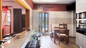 A modern kitchen with a dining area, a TV mounted above the counter, and a view through the open door. - Holiday Home 'Porto Douro' with Private and Indoor Pools, Heated Water, Terrace and Wi-Fi (Foz do Sousa)