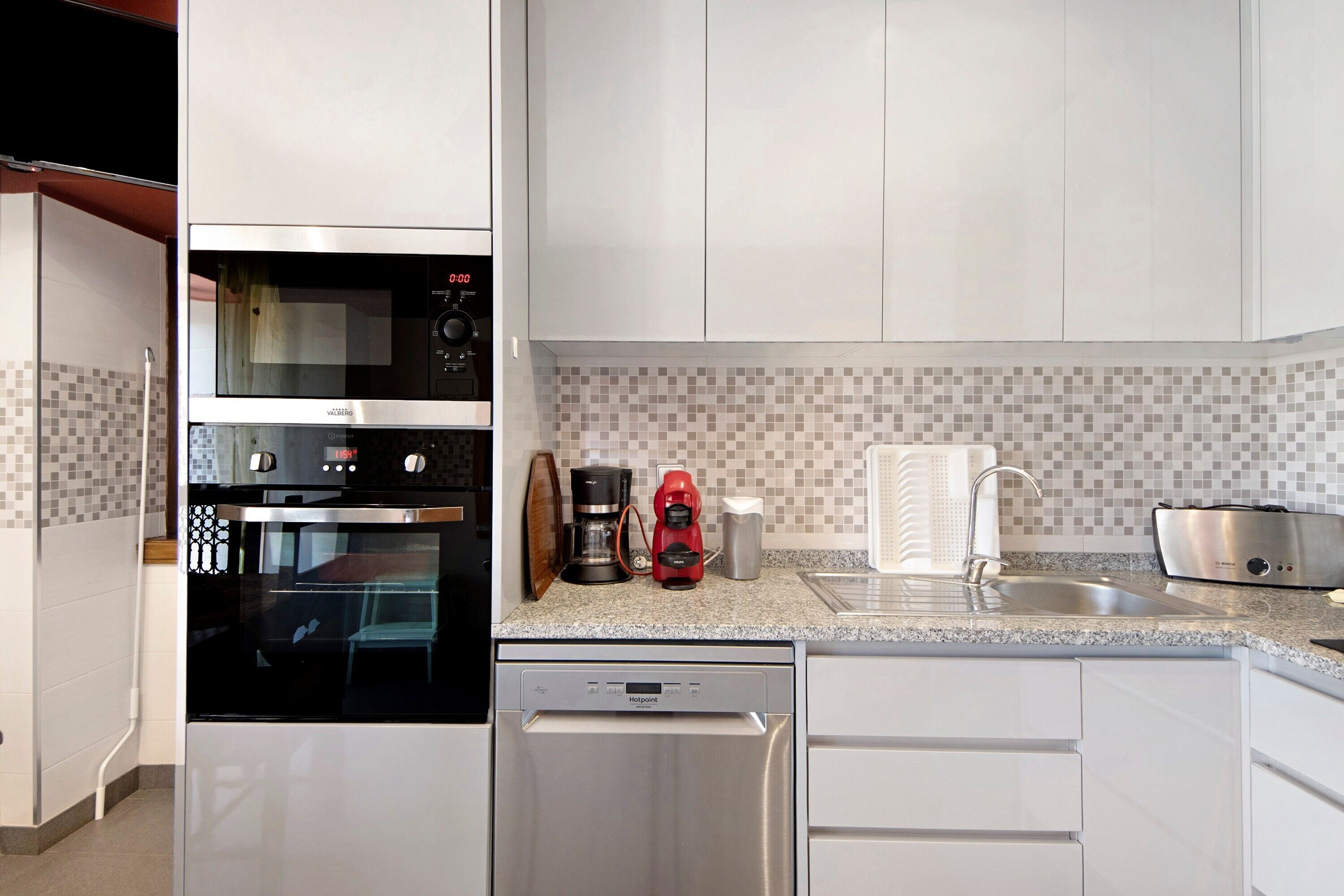 A modern kitchen with stainless steel appliances, a dishwasher, a coffee maker, and a toaster.