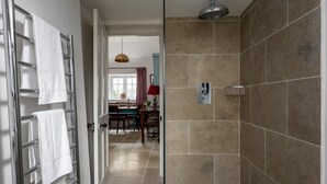 Un baño con ducha, paredes enlosadas y un perchero para toallas.
