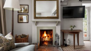 Una sala de estar con chimenea, un televisor montado en la pared y una zona de estar acogedora.