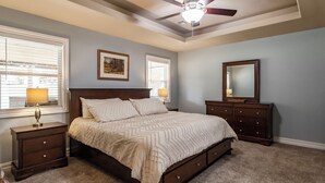 A bedroom with a bed, nightstands, a dresser, a ceiling fan, and two windows with blinds. - Lakeview Home in serene setting, 3 mi to Grove! Perfect for families & fishermen (Grove)