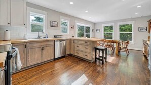 Una cocina amplia con armarios de madera, lavavajillas y un comedor con mesa y sillas.