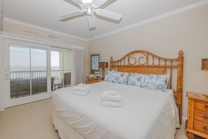 Une chambre dotée d’un grand lit, d’un ventilateur de plafond, d’une table de chevet et offrant une vue sur l’extérieur grâce à une porte-fenêtre coulissante.