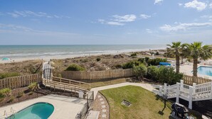 Ein Poolbereich mit Holzterrasse, einem kleinen Pool und Blick auf Strand und Meer.
