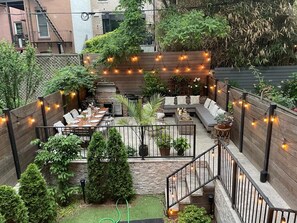 A cozy backyard with a wooden deck, outdoor seating, and string lights.