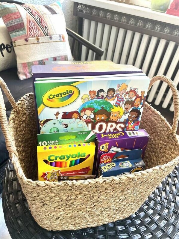 A woven basket containing various educational toys and books, including Crayola products.