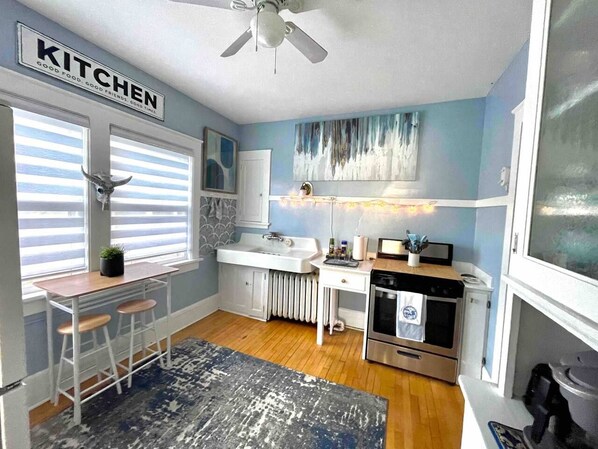 A kitchen with a white countertop, a stove, a sink, and a ceiling fan.