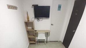 A bedroom with a bed, a desk, a chair, and a TV mounted on the wall. - Hotel Primavera Zero (Medellín)
