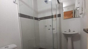 A bathroom with a glass-enclosed shower, a toilet, and a sink. - Hotel Primavera Zero (Medellín)