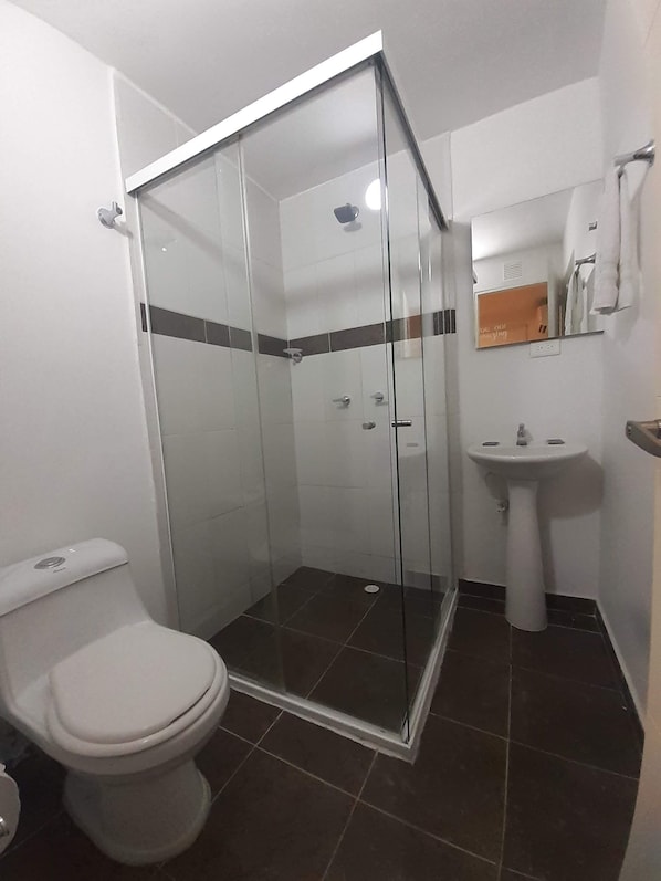 A bathroom with a glass-enclosed shower, a toilet, and a sink. - Hotel Primavera Zero (Medellín)
