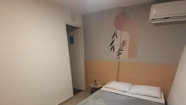 A bedroom with a bed, a nightstand, and a wall-mounted air conditioner. - Hotel Primavera Zero (Medellín)