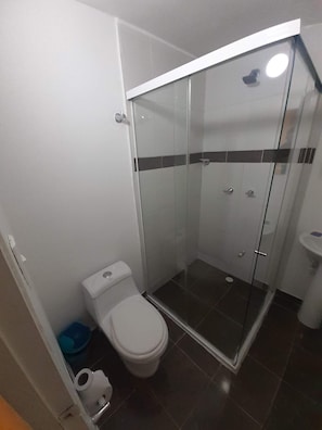 A bathroom with a glass-enclosed shower, a toilet, and a sink. - Hotel Primavera Zero (Medellín)