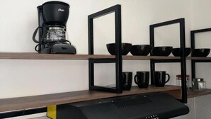 A kitchen with a coffee maker on a shelf, black bowls, and mugs on a black shelf unit. - Cozy 3-bedroom condo in enchanting Santa Rosa de Cabal with WiFi (Santa Rosa de Cabal)