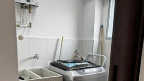 A compact laundry room with a front-loading washing machine, a sink, and a window. - Cozy 3-bedroom condo in enchanting Santa Rosa de Cabal with WiFi (Santa Rosa de Cabal)