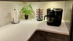 A kitchen with a coffee maker, a potted plant, and a coffee pod holder. - Waterfront Log Home with Beach and Hot Tub. Pet Friendly! (Clandeboye)