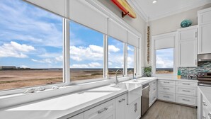 A modern kitchen with large windows, white cabinetry, and a view of the beach. - Call Me The Breeze - Private Home At The Shores 3 Bedroom Home by RedAwning (South Padre Island)