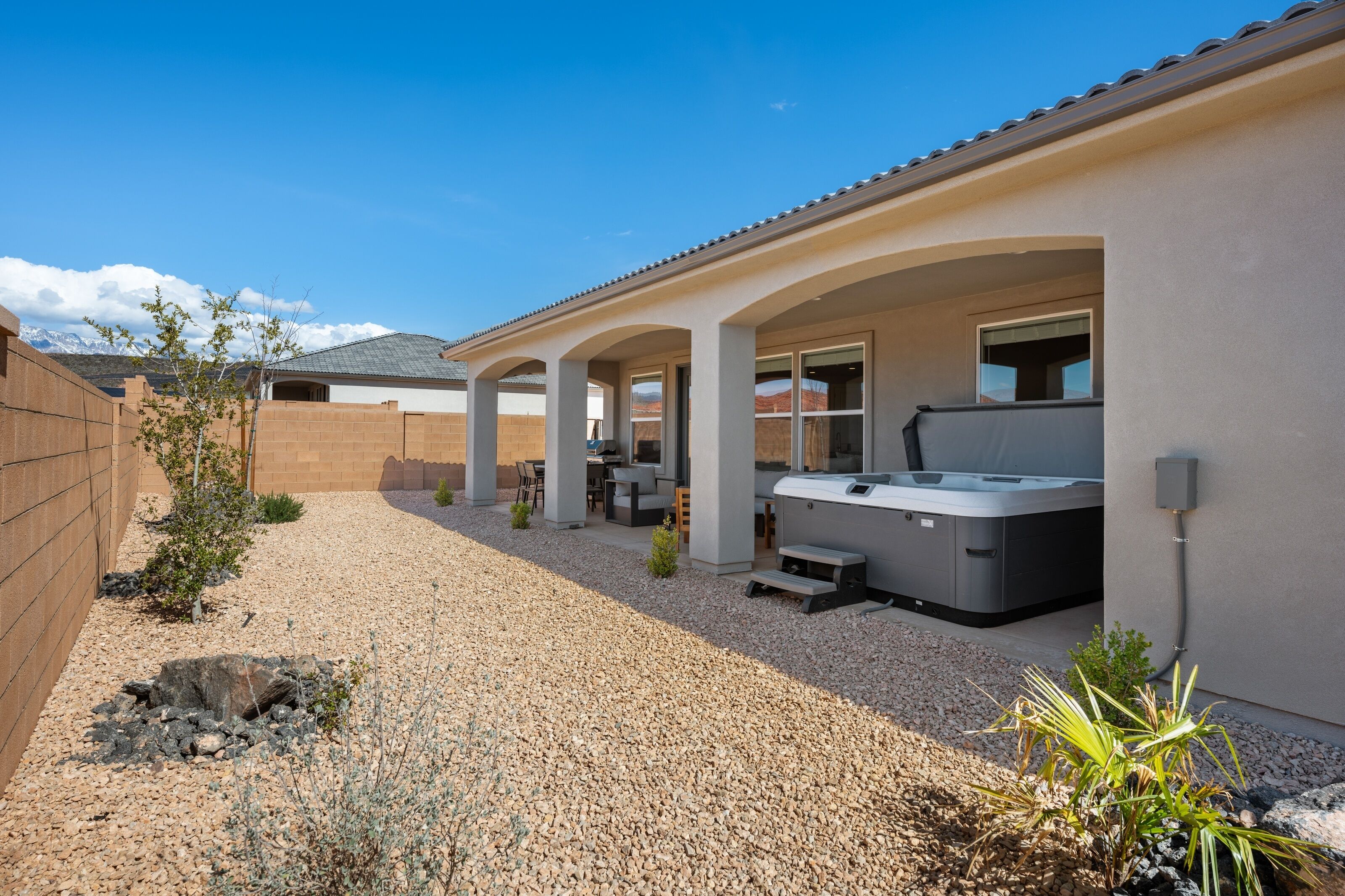 A covered patio area with a hot tub, seating, and a view of mountains.