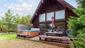 A wooden cabin with a hot tub, outdoor seating, and a deck. - Waterfront Loon Cottage | Private Boat Dock | Hot Tub (Island Park)
