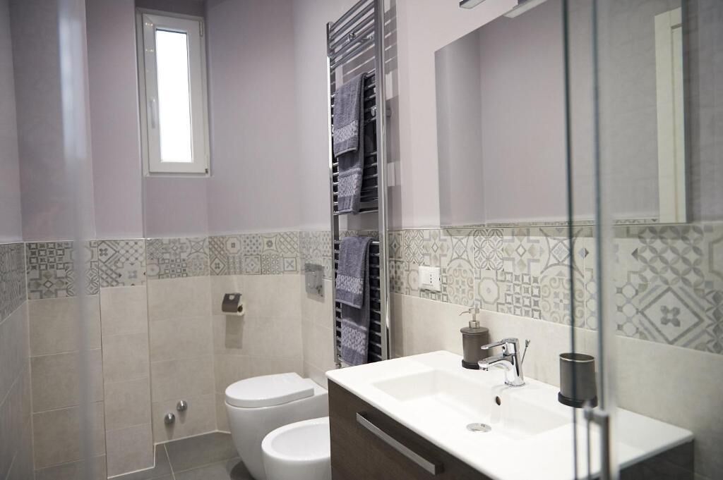 A bathroom with a toilet, a sink, and a towel rack.