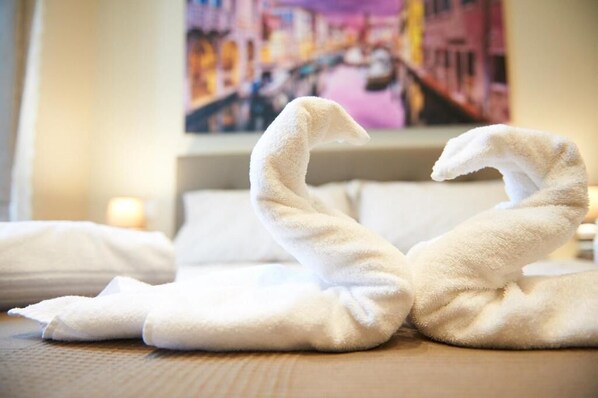 Two swan-shaped towels on a bed with a painting in the background. - Miramare Luxury Suites (Trieste)