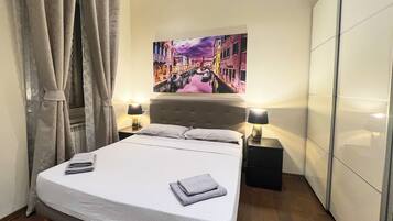 Ein Hotelzimmer mit einem Bett, zwei Nachttischlampen, einem Bild an der Wand und einem Kleiderschrank.