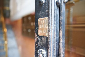 A close-up of a metal door with a brass plaque that reads "SI CHUDE DA SE". - Miramare Luxury Suites (Trieste)