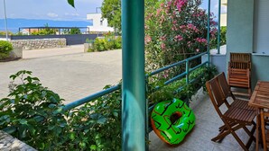 A patio area with a table and chairs, a green inflatable pool float, and a view of a road and buildings in the background.