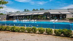 A swimming pool with lounge chairs and a covered seating area.