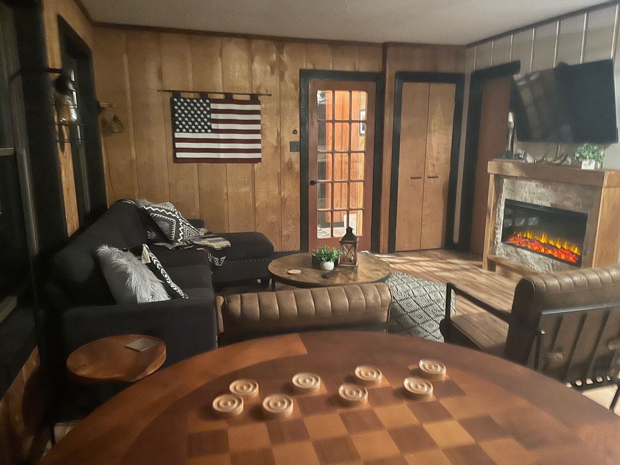 Una sala de estar acogedora con chimenea, una mesa a cuadros y un sofá.