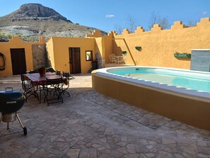 A patio with a pool, stone flooring, a barbecue grill, and outdoor furniture. - Cortijo rural los Cerezos, pueblo Taberno (Albox)